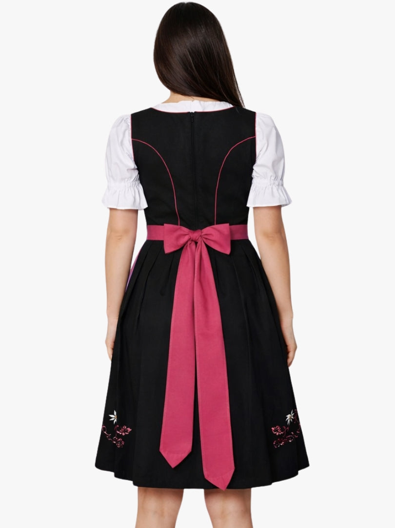 Front view of women's black Bavarian dirndl dress with white puff sleeve blouse, pink lace-up bodice, and pink apron.